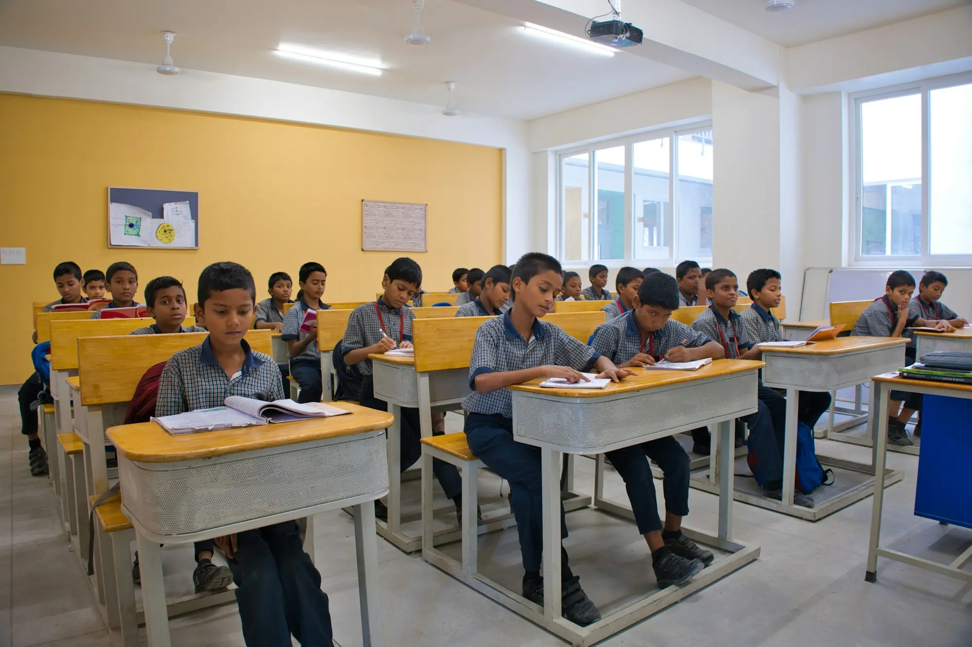 Students in uniform at their desks in a bright, modern classroom.