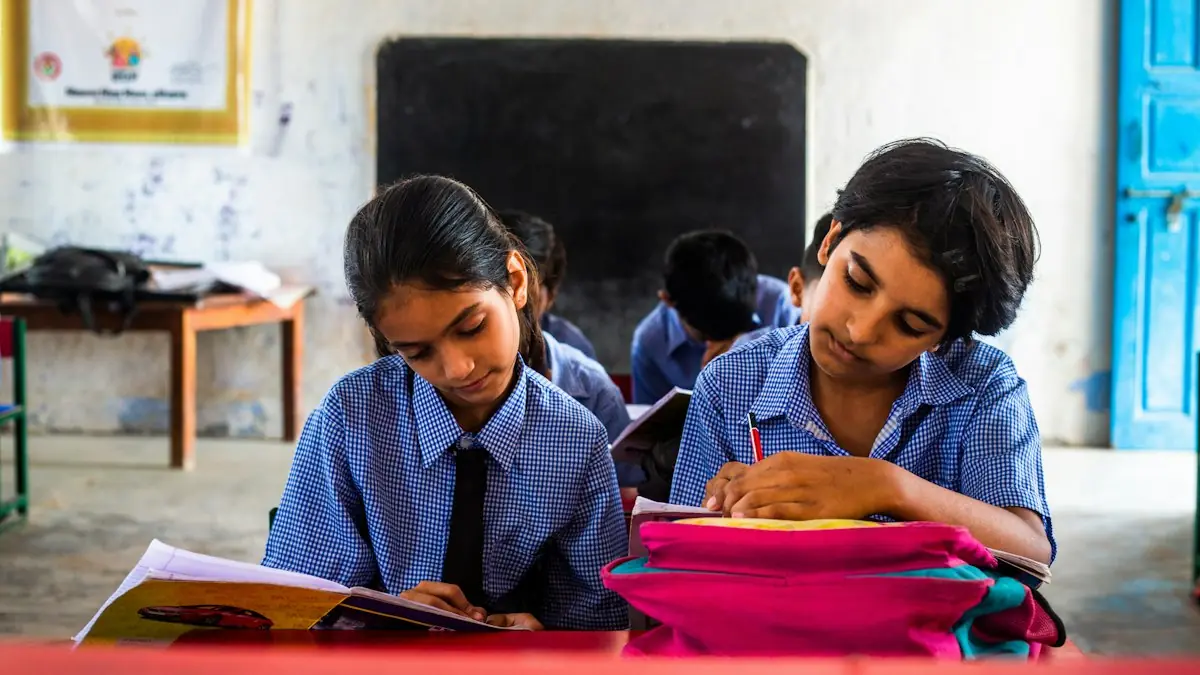 Two students writing in their notebooks at a classroom desk.